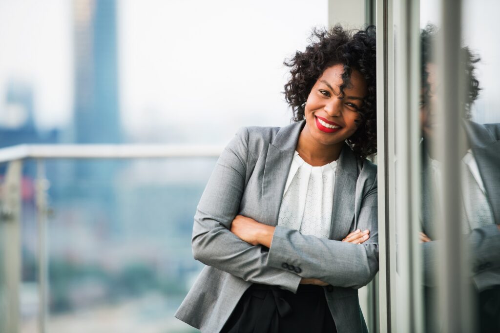 A portrait of a businesswoman standing on a terrace, arms crossed.