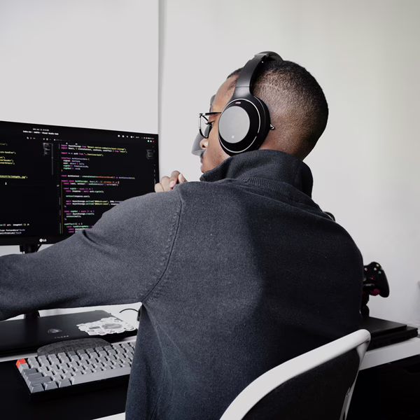 MWD - Black Young Man Working On A Desktop with Headphones On