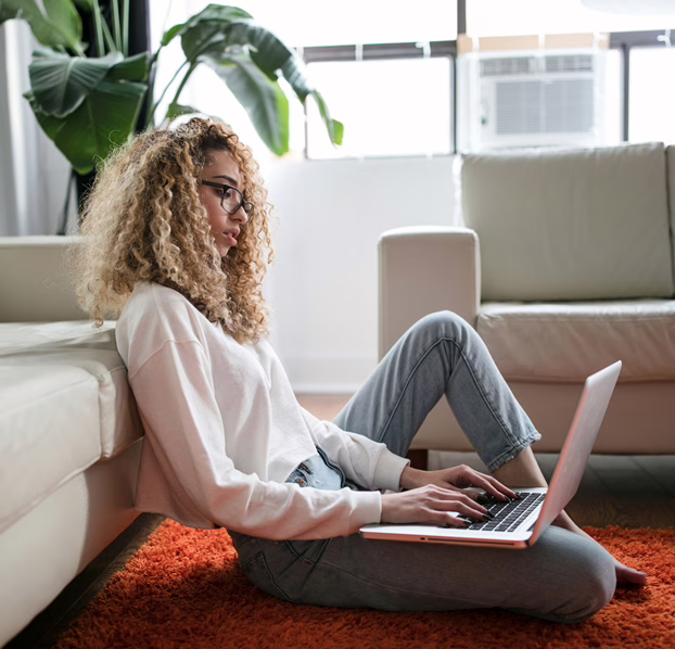 MWD - Young White Lady Seated on the Floor Working on her Laptop