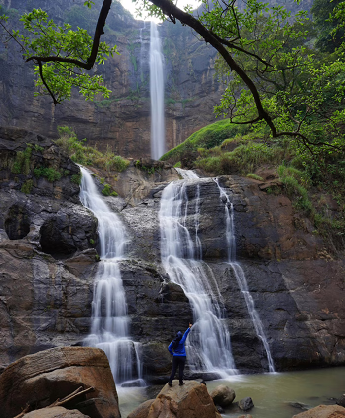 Femme debout au pied d'une chute d'eau