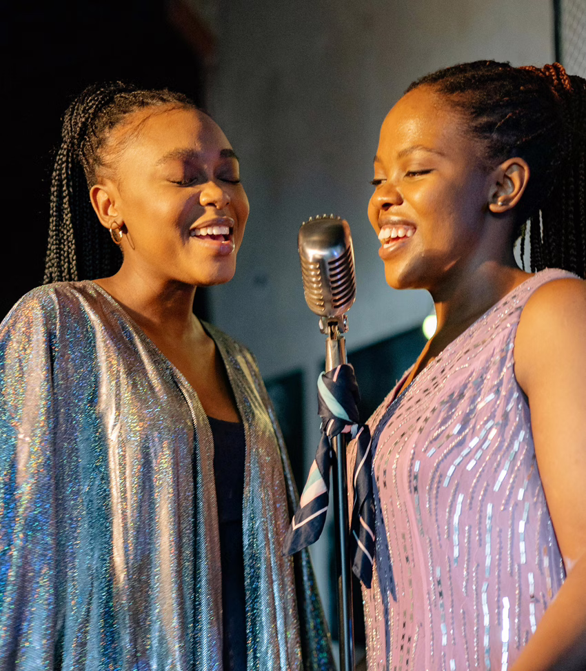 MWD - Deux jeunes femmes chantant en partageant un microphone